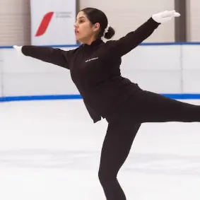 Patinadora con experiencia realizando una posición de equilibrio sobre el hielo
