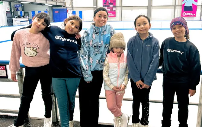 Grupo de niñas de Ice Gravity reunidas junto a la pista de hielo