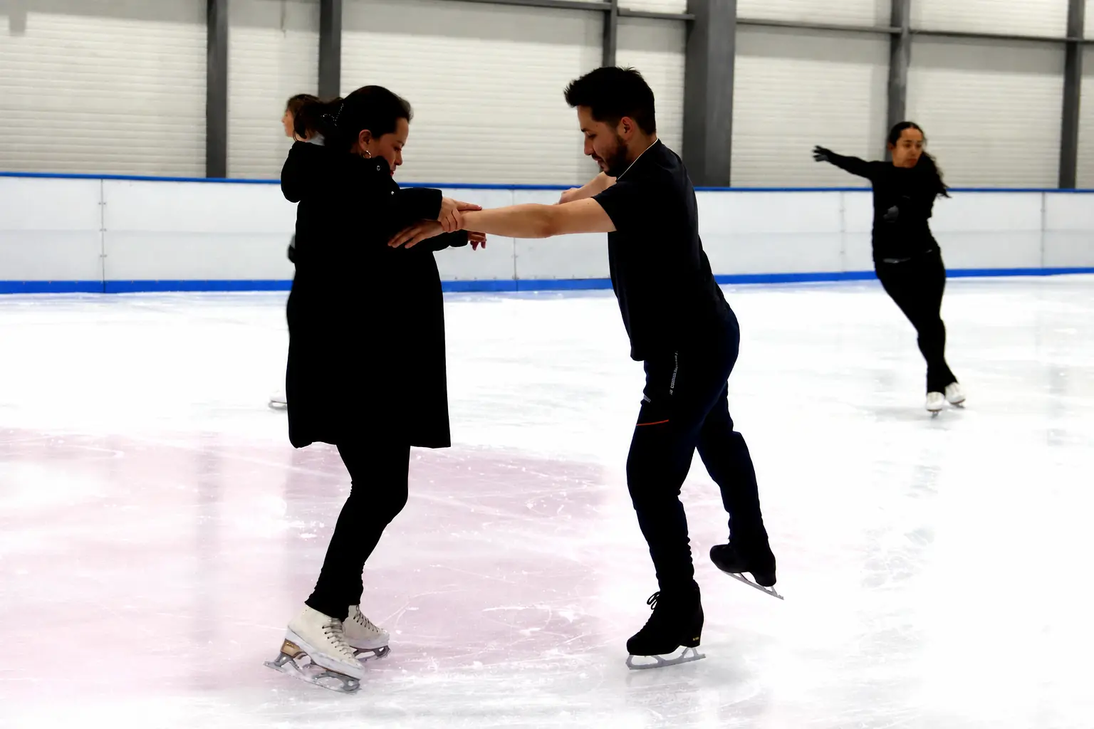 Entrenadora acompañando a un patinador durante una práctica de Ice Gravity